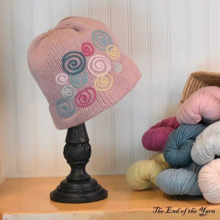 Handmade pink hat on a stand.