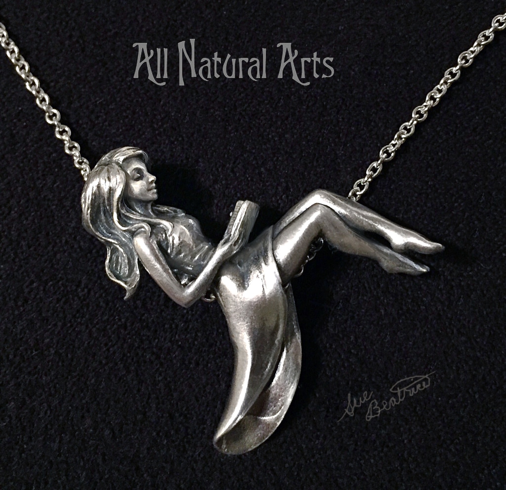 Silver girl pendant reclining on silver chain reading a book.