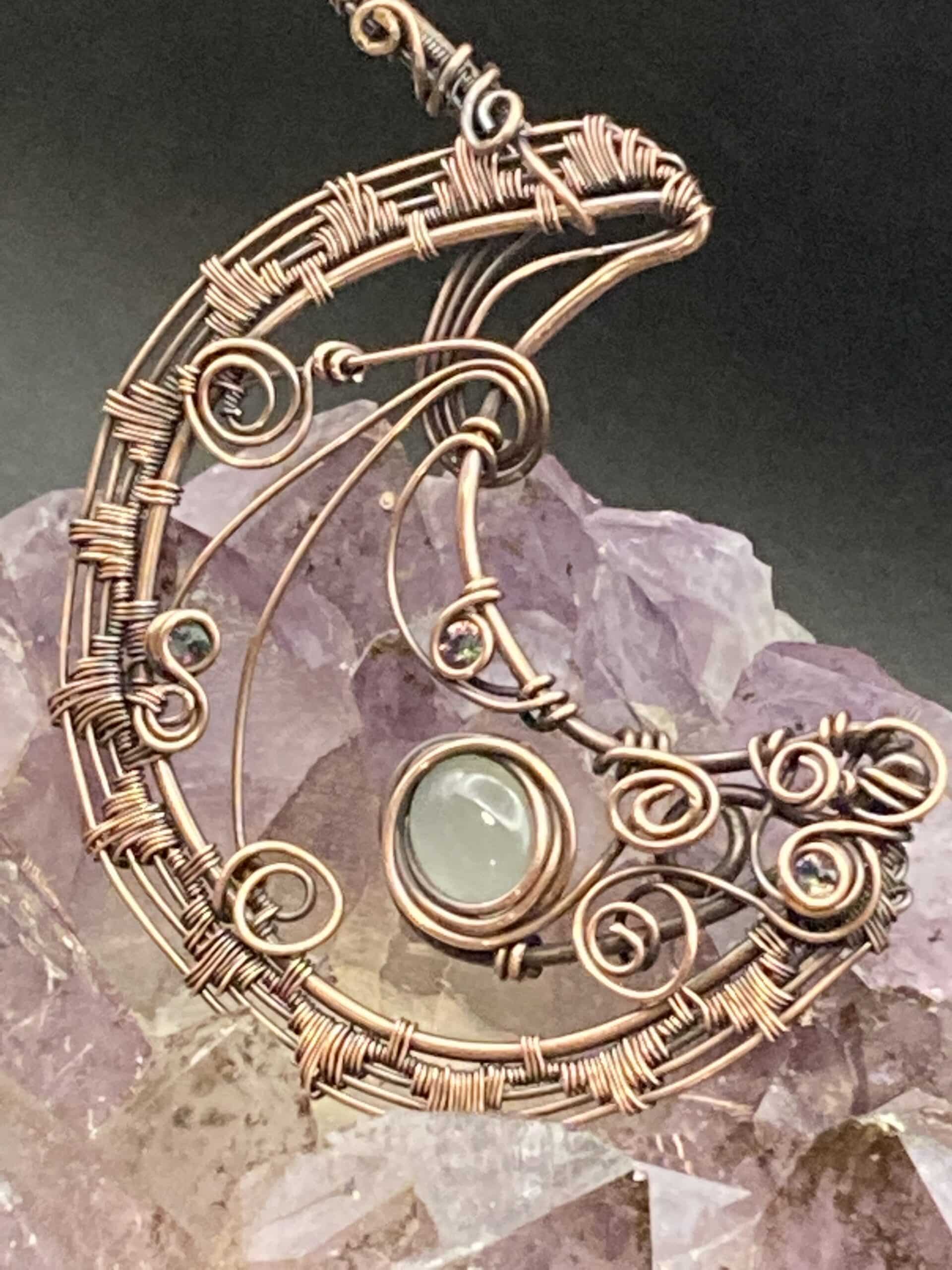 Woven Moon pendant with Chalcedony stone and three inset facet Mystic Jewels. Measures 2-1/2" round at the larges. It is almost a 3-quarter moon shape. Includes a hand wrapped adjustable cord necklace.