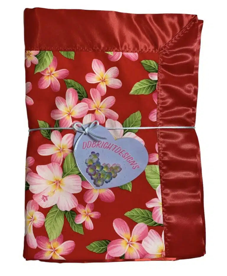 Silky smooth satin trims the edge of this beautiful red Hawaiian print baby blanket which is backed in a soft 100% cotton flannel in white with tiny pink hearts.