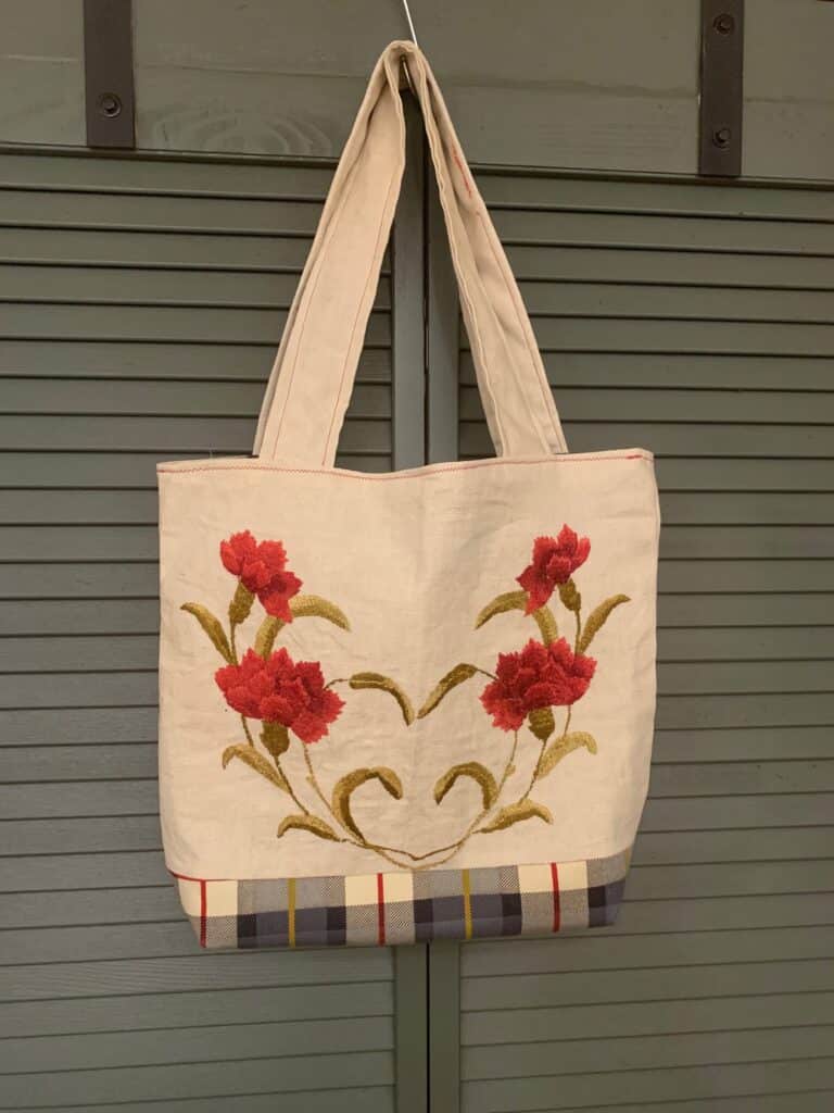 linen tote with red embroidered flowers and blue plaid base