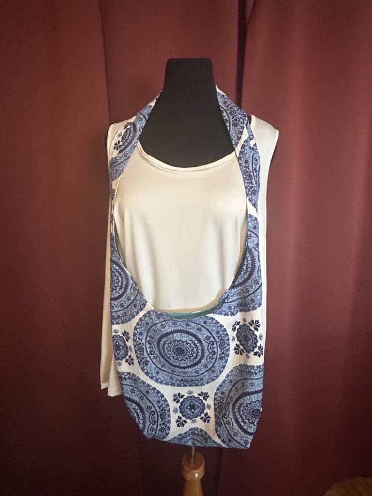 This hippie bag is the perfect carry all for everyday use. Features a 2" wide strap that can be worn over the shoulder for comfort and style. The boho purse measures 36" long from the top of the strap to the base of the purse. The purse body is 16" x 16." This boho purse is fully lined in a patchwork pattern of cotton fabrics in shades of blue. Pockets on each side made of the mandala floral upholstery fabric. Pockets measure 6" x 6" perfect size for a cell phone, keys or sunglasses. The magnetic snap closure keeps belongings secure.