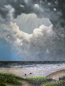 Seascape with a low horizon. The foreground is filled with sea grasses and a few boulders. There are two rocks in the breaking surf. The clouds are in a circular motion starting from the horizon with dark to light. In the center top of sky and behind the top dark cloud are rays of sun light beaming down