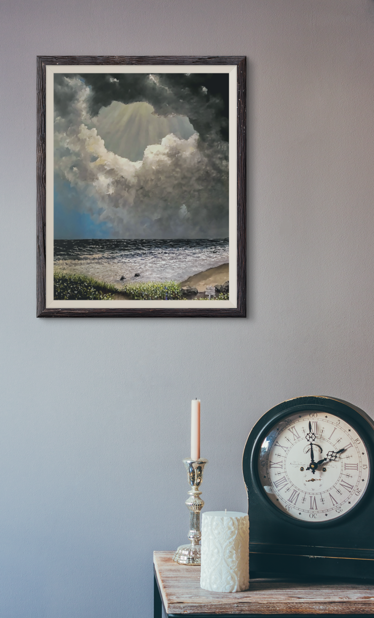 Seascape with a low horizon. The foreground is filled with sea grasses and a few boulders. There are two rocks in the breaking surf. The clouds are in a circular motion starting from the horizon with dark to light. In the center top of sky and behind the top dark cloud are rays of sun light beaming down