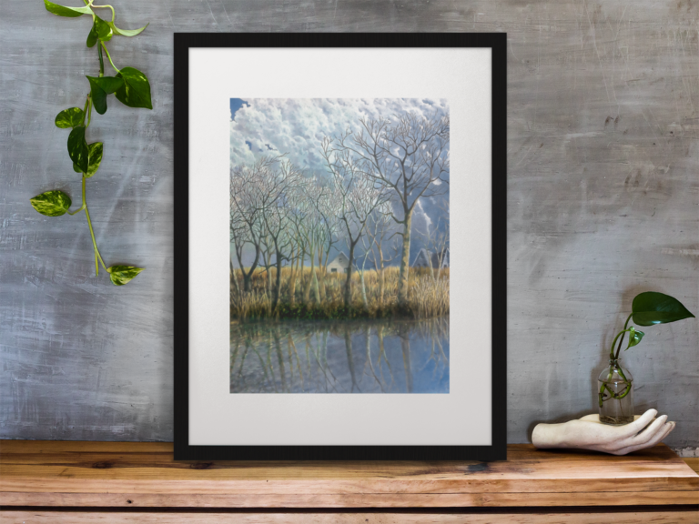 Image of a calm early March river with reflections of leafless trees. The river bank has tall Winter grasses. The grasses extend further inland which partially hides the two house in the near background. The sky is of a vertical moving clouds.