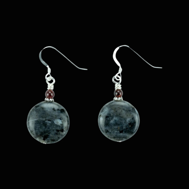 Labradorite earrings on a black background. The earrings have silver ear wires and are made from gray labradorite coin beads and are accented with a small garnet bead on the top of the labradorite coin bead.