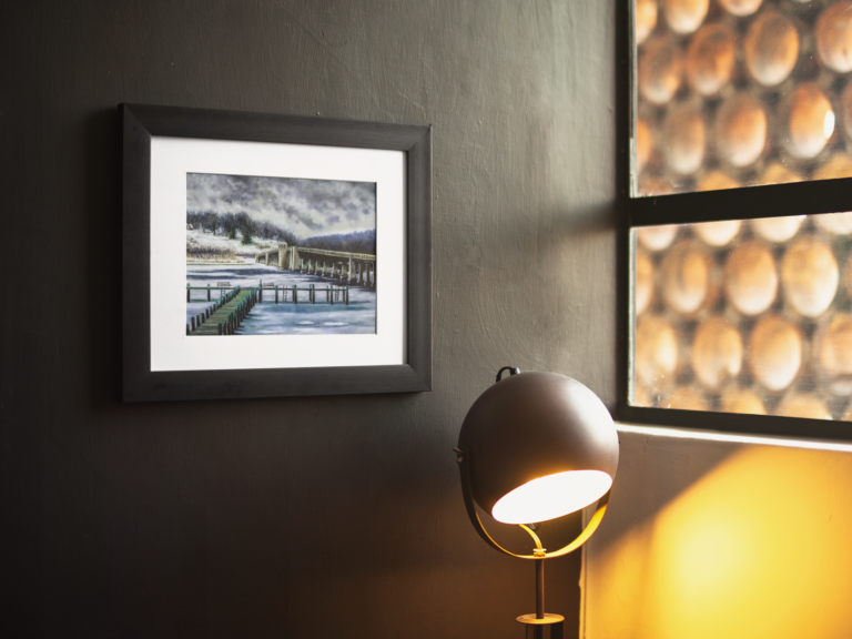 framed art print mockup on a black wall near a lamp a14687