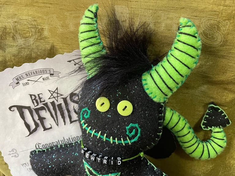 Bedevils. Name Pewtrid. Sparkle black felt body with bright green accents. Front view close up of face.