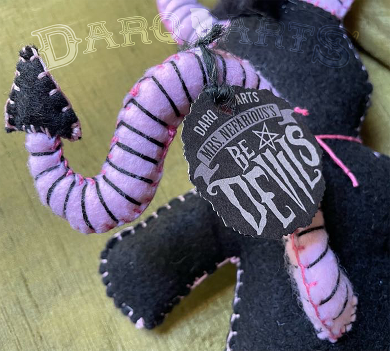 Bedevils. My name is Chagrin. I have a black felt body with piggy pink accents. Back view close up.