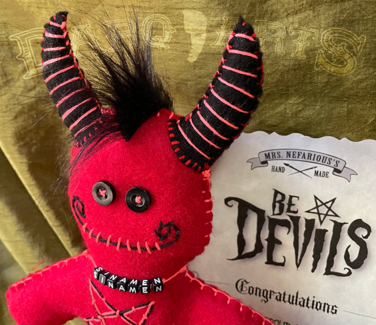 Bedevils - Sinamen. Bright red soft felt body with black horns, tail, hooves and reversed pentagram. Close up of face.
