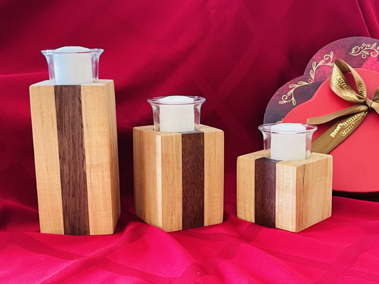 3 handcrafted wood votive candleholders on a red background with a heart-shaped candy box in the background