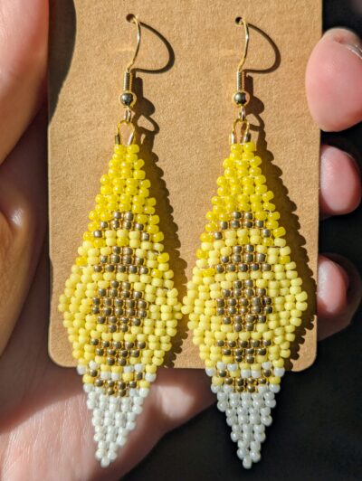 A pair of diamond-shaped yellow ombre beaded earrings with gold moon phases in the center of each.