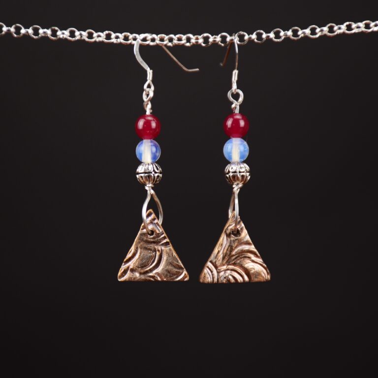 Handcrafted one of a kind fine silver earrings. These have a triangular shaped patterned piece of fine silver as the main part of the earrings. These are topped by a white opaline bead and a genuine ruby bead. The earrings feature Sterling Silver French ear wires.