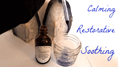Amber tincture bottle labeled “Chamomile, Lemon Balm and Blue Butterfly Pea” next to a glass with purple liquid, set between two crystal geodes with the words “Calming,” “Restorative,” and “Soothing” written on the background.