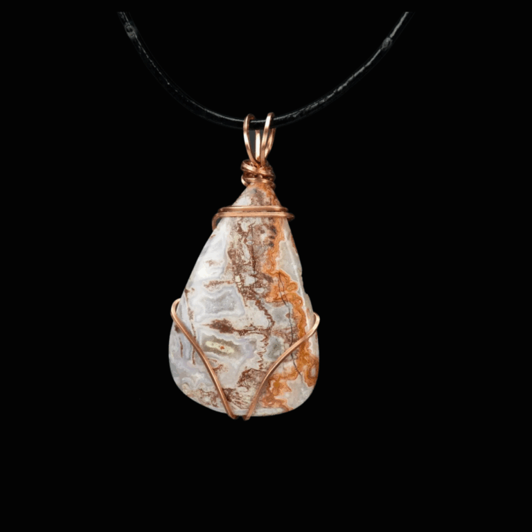 Brown and white teardrop stone minimally wrapped in copper wire. The pendant is shown on a black leather cord and is pictured on a black background.