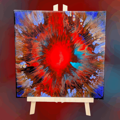 A 12x12 fluid art painting displayed on a wooden easel: the colors include reds and oranges, ultramarine blue, turquoise, periwinkle, and gold.