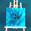 "Undertow", a blue monochrome 8x8 fluid art painting displayed on a wooden easel.