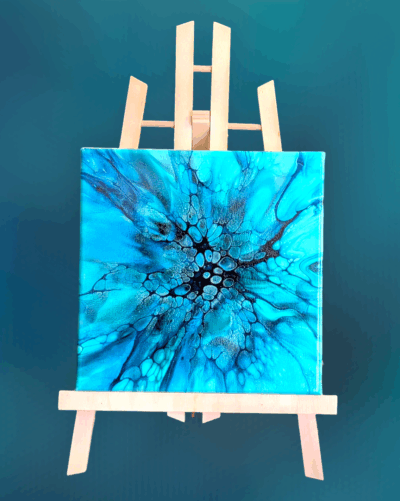 "Undertow", a blue monochrome 8x8 fluid art painting displayed on a wooden easel.