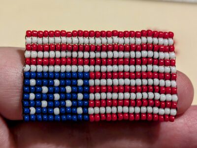 The front of the beaded distress flag pin.