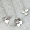 three sterling silver flower pendant necklaces flat on a gray background