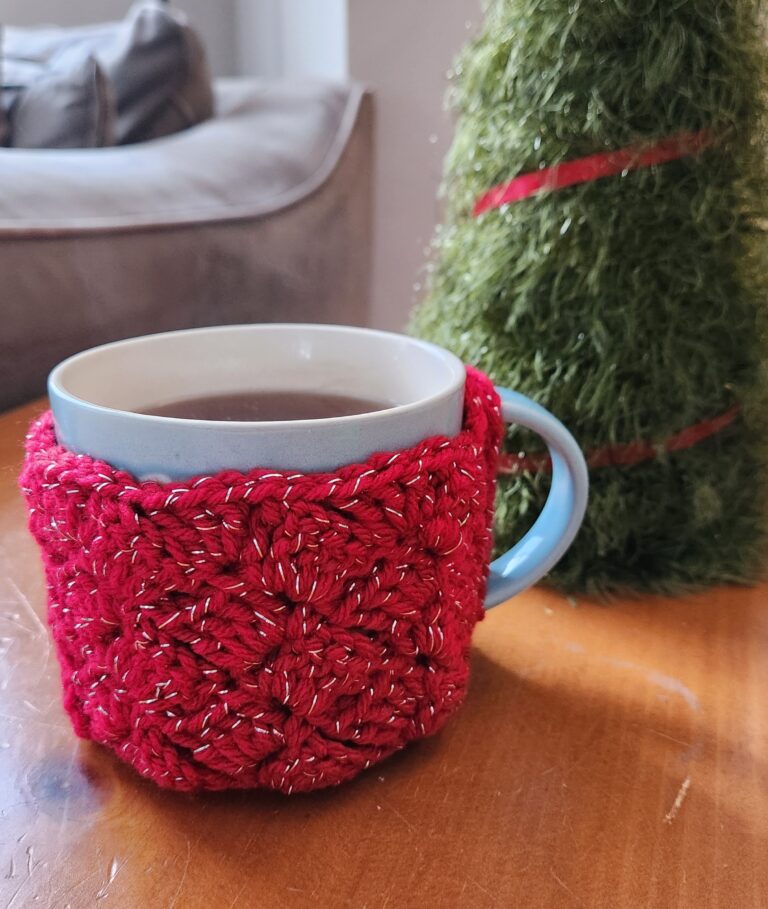 Crochet Mug Cozy - Many Colors! 1 Mug of tea with a red crochet cozy on it, sitting on a table.