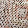 Close up of granny stitches on a shawl in varying colors of cream, pink and light brown