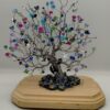Back view of peacock wire tree. Silver tree with colorful and sparkly beads on wooded base.