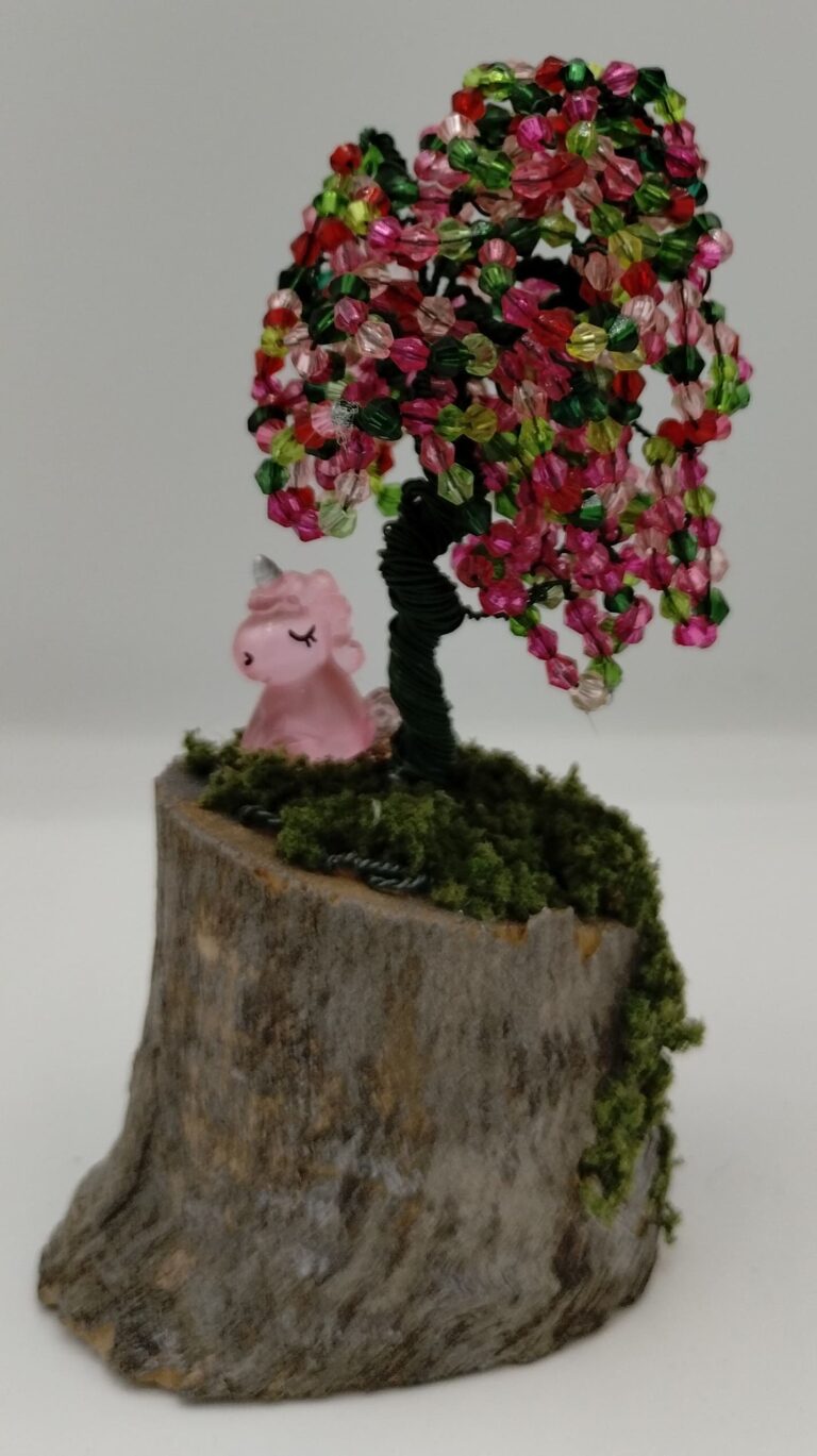 Beaded green wire tree with green, pink and red beads. On a birch base with moss and a unicorn sitting under the tree.