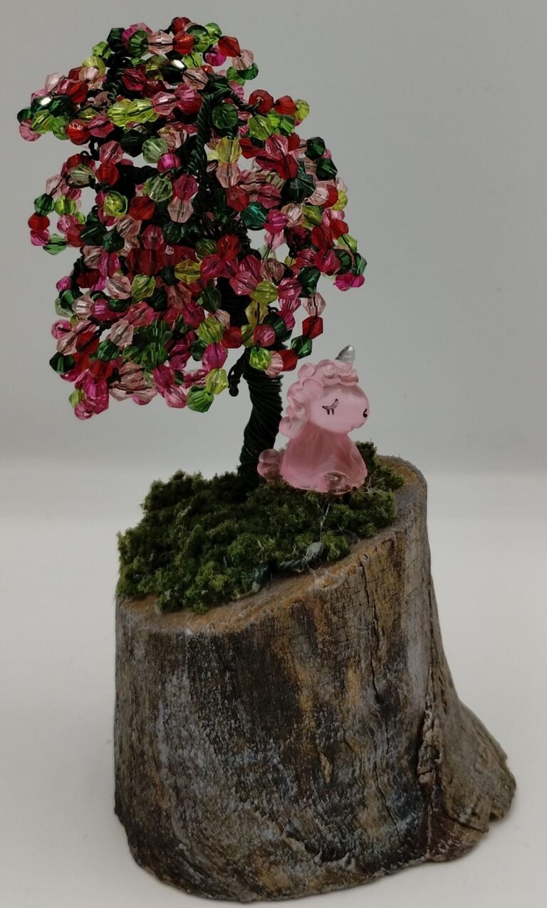 Green spring themed wire tree. With green and pink beads on a weathered birch base with moss. A small pink unicorn sits under the tree.