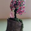 Wire tree made with green wire and red, green and pink beads. With a small pink unicorn sitting under the tree.