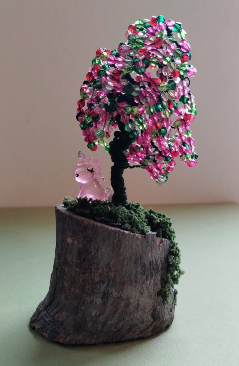 Wire tree made with green wire and red, green and pink beads. With a small pink unicorn sitting under the tree.