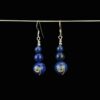 Deep blue lapis lazuli earrings created with three beads. The bottom bead is 12mm the middle bead is 8mm and the top lapis bead is 6mm. There is a handcrafted sterling silver swirl on each of the 12mm beads. The earrings have sterling silver French ear wires and they are hanging from a chain for display.