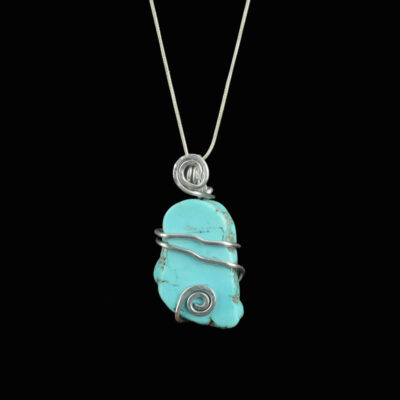 Turquoise pendant with a silver colored wrap with two strands of wire across the middle with slight bends in the wire and a silver swirl at the top in front of the bail and another silver swirl at the bottom of the pendant.