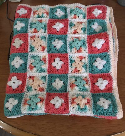 Charming handmade crochet afghan in soft pink and mint green, perfect as a baby blanket or a cozy lapghan.