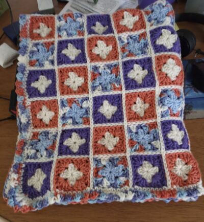 Radiant and beautifully handmade, this purple-and-orange crochet baby blanket brings a burst of color and joy to any nursery